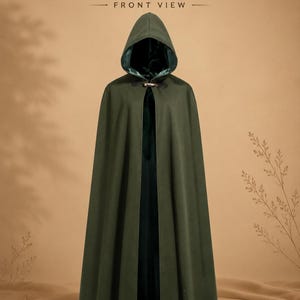 May include: A floor-length olive green hooded cloak featuring a dark green interior lining and a metallic toggle clasp at the neck. The text HOODED CLOAK FRONT VIEW is displayed at the top of the image. The garment has a structured hood and drapes.