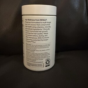 May include: A white cylindrical supplement bottle with a white screw-top lid. The label features black text detailing Hair Wellness from Within, physician-formulated ingredients, dosage instructions, and safety warnings for this dietary product.