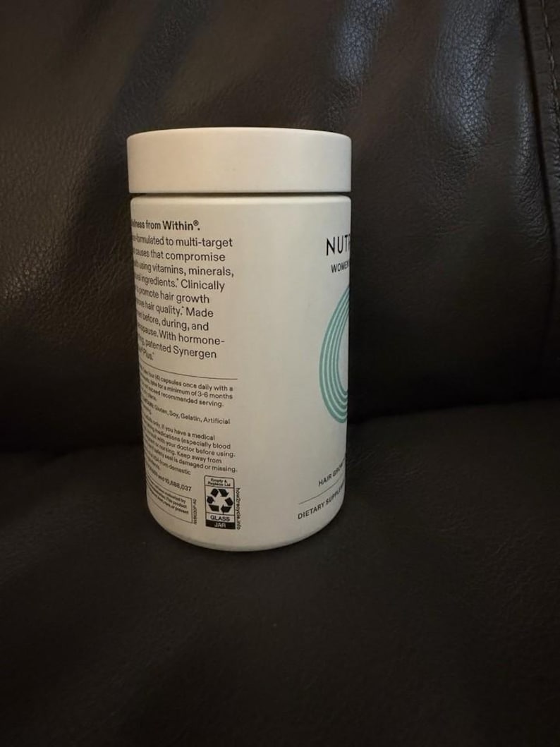 May include: A white cylindrical supplement bottle with a flat lid. The label features black text detailing product information, including the phrase Wellness from Within, and a teal circular graphic. The bottle is made of glass and includes a recycling icon.