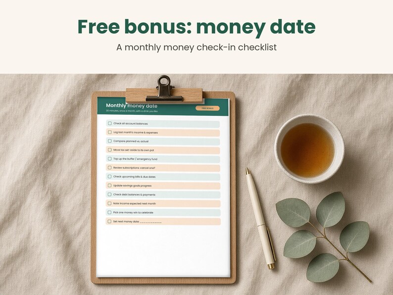 May include: A wooden clipboard holding a Monthly money date checklist with alternating light blue and peach rows, featuring a white pen and a small cup of tea nearby. The text reads Free bonus: money date, A monthly money check-in checklist.