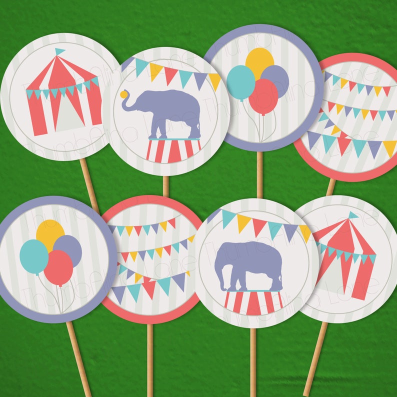 May include: Set of eight printable circus party cupcake toppers. The toppers feature a red and white striped tent, a purple elephant on a red and white striped platform, a string of colorful flags, and balloons in purple, yellow, and blue.