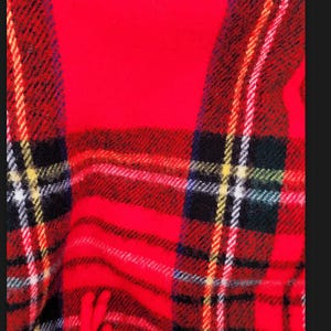 May include: A textile fabric featuring a vibrant red base colour with a classic plaid pattern. The design consists of intersecting black, white, and yellow lines that create a grid effect across the surface. The material has a soft, fuzzy texture.