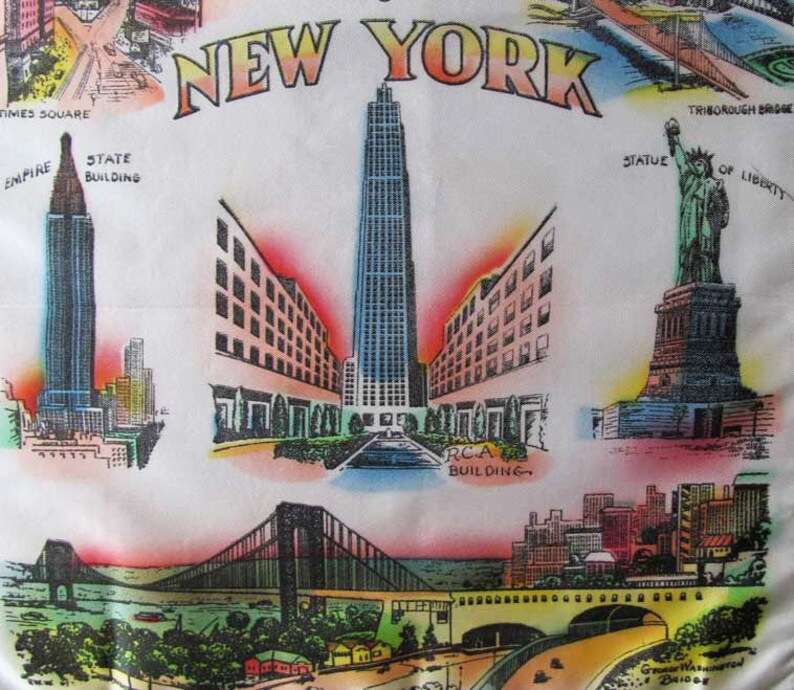 May include: White fabric featuring colorful illustrations of New York City landmarks. The design includes the Empire State Building, the Statue of Liberty, and the RCA Building, with the text "NEW YORK" at the top.