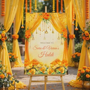May include: A rectangular welcome sign on a gold metal easel featuring a yellow and orange floral theme with hanging bells and curtains. The text reads: WELCOME TO Sara & Varun's Haldi. The design includes illustrations of marigold flowers.