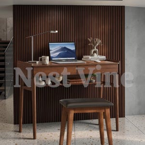 May include: A wooden desk with two drawers and a lower shelf, featuring a silver desk lamp, a laptop, a white mug, a decorative vase, and books on top. A matching wooden stool with a dark brown padded seat is positioned in front of the desk.