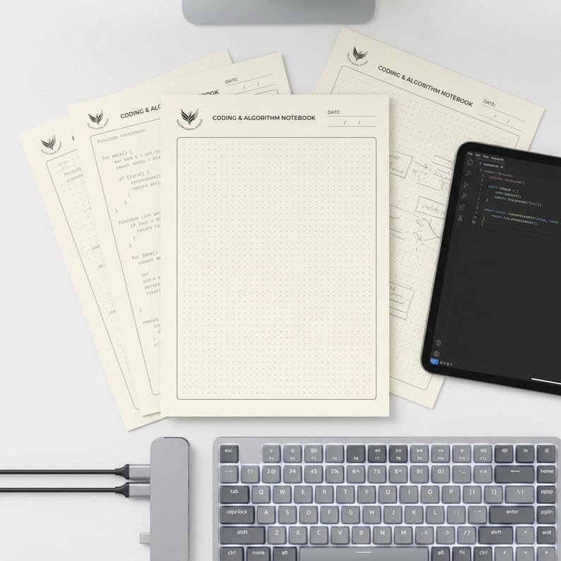 May include: A set of cream-coloured Coding & Algorithm Notebook pages featuring a dot grid pattern, a header with a logo, and a date field. The pages are arranged with a black tablet displaying code and a grey keyboard visible in the foreground.