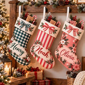 May include: Three Christmas stockings hanging from a wooden mantel. The first is green and white checked with the name Henry. The second is red and white striped with the name Noah. The third is pink with floral patterns and the name Olivia.