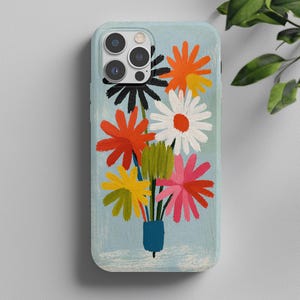 May include: A light blue phone case featuring a painted bouquet of flowers in vibrant colors including orange, white, red, yellow, pink, and black. The flowers are arranged in a small blue vase, with visible brushstroke textures throughout the design.