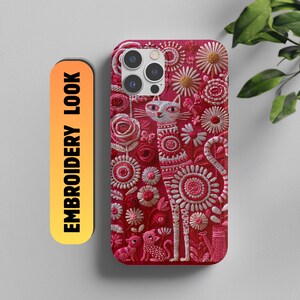 May include: A smartphone case featuring a vibrant red background with a detailed white and pink embroidered-style pattern of a large cat, two smaller cats, and various floral motifs. The text EMBROIDERY LOOK is printed on a yellow vertical tag.