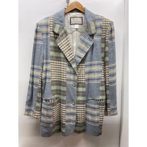 May include: A long-sleeve blazer featuring a patchwork design of blue, green, and beige plaid and striped patterns. The garment has a notched lapel, two front buttons, and two lower pockets. A label inside the neck reads Lilli Ann Jefferies.