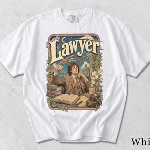 Könnte beinhalten: Ein weißes T-Shirt mit einer grafischen Illustration einer Person im Anzug, die an einem Schreibtisch mit Büchern, einem Hammer und einer Tasse sitzt. Der Text lautet "Lawyer" und "I object to doing work" in einer dekorativen Schrift. Das Design zeigt einen Sternenhimmel.