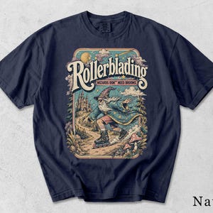 Op de afbeelding: Een marineblauw t-shirt met een grafische print van een tovenaar op rolschaatsen. De tekst luidt "Rollerblading" en "Wizards Don't Need Brooms". De illustratie bevat een kasteel, een maan, sterren, wolken, bomen en paddenstoelen in een kleurrijke, gedetailleerde stijl.