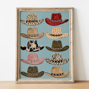 Könnte beinhalten: Ein gerahmter Kunstdruck mit zehn illustrierten Cowboyhüten, die in zwei Spalten vor einem hellblauen Hintergrund angeordnet sind. Die Hüte zeigen verschiedene Muster und Farben, darunter Leopardenmuster, einfarbiges Rot, Beige, Kuhflecken, Olivgrün, Rosa, Zebramuster und Braun.