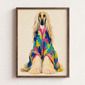 Könnte beinhalten: Ein gerahmter Kunstdruck, der einen langhaarigen Afghanischen Windhund mit cremefarbenem Fell zeigt. Der Hund trägt einen leuchtend bunten, floral gemusterten Mantel mit einem leuchtend rosa Saum vor einem einfarbigen, hell cremefarbenen Hintergrund.
