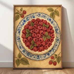 Könnte beinhalten: Ein gerahmter Kunstdruck mit einer Himbeertorte, die auf einem blau-weiß gemusterten Teller mit Blumenmotiv zentriert ist. Der Hintergrund ist strukturiert beige und mit kleinen Illustrationen von Himbeerzweigen verziert.
