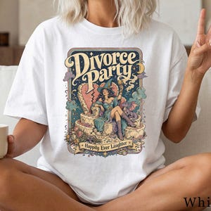 Könnte beinhalten: Ein weißes T-Shirt mit einem farbenfrohen Grafikdruck mit dem Text Divorce Party und Happily Ever Laughter. Die Illustration zeigt eine Person mit Hexenhut, die auf einem Thron in Form eines gebrochenen Herzens neben einem kleinen Drachen sitzt.