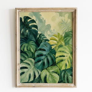 Könnte beinhalten: Ein gerahmter Wandkunstdruck mit einer dichten Ansammlung von Monstera-Blättern in verschiedenen Schattierungen von tiefem Waldgrün, Smaragd und blassem Limettengrün. Das Laub ist vor einem weichen, gelben und cremefarbenen Hintergrund angeordnet.