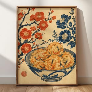 Könnte beinhalten: Ein gerahmter Wandkunstdruck mit einer Schüssel goldbrauner frittierter Lebensmittelbällchen mit sichtbaren geraspelten Zutaten. Der Hintergrund zeigt eine cremefarbene Papierstruktur mit Illustrationen roter Pflaumenblüten und dunkelblauer Blumenmuster.
