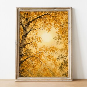 Könnte beinhalten: Ein gerahmter Kunstdruck, der eine Birke mit goldgelben Herbstblättern vor einer hellen, dunstigen Sonne zeigt. Das Bild zeigt dunkle Äste im Kontrast zum warmen, leuchtenden Laub und einen Rahmen aus hellem Holz.
