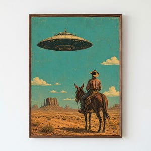 Pode incluir: Uma impressão de arte emoldurada retratando uma paisagem desértica com uma pessoa usando um chapéu de cowboy e camisa xadrez montada em uma mula. Um grande disco voador metálico em forma de disco paira no céu azul-petróleo sobre mesas.