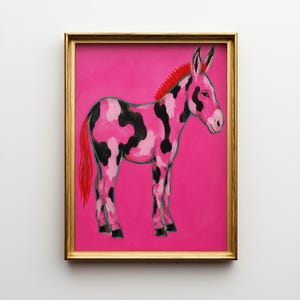 Op de afbeelding: Een ingelijste kunstdruk met een gestileerde ezel tegen een levendige felroze achtergrond. De ezel heeft een vacht met patronen van zwarte, lichtroze en donkerroze vlekken, met een felrode manen en een bijpassende rode staart.