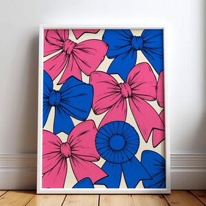 Könnte beinhalten: Ein gerahmter Wandkunstdruck mit einem sich wiederholenden Muster aus leuchtend rosa und hellblauen Schleifen auf cremefarbenem Hintergrund. Die Illustration zeigt mehrere große, detaillierte Schleifen und eine einzelne blaue Rosette.