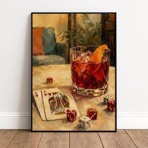 Könnte beinhalten: Ein Ölgemälde-Druck, der ein Glas mit rotem Cocktail und einer Orangenscheibe, zwei Spielkarten mit dem Herz-Ass und dem Herz-König sowie mehrere verstreute rote und weiße Würfel auf einem Tisch zeigt, gerahmt in einem dünnen schwarzen Rand.