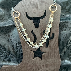 Chunky antiqued white floral Charms with gold color beads paired with a double gold chain and a pearl gold colored chain Bootlets.