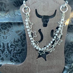 Chunky silver tone open star chain paired with a double chain with a silver tone chain and strand of pearls compliment these Bootlets.