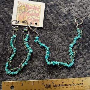 May include: Two turquoise chip bead chains with iridescent metal wire and silver-tone rings, attached to a white display card labeled Bootlets and Bearings by Joelle Joden. A yellow ruler shows the chains measure approximately 8.5 inches in length.