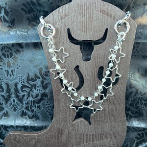 Chunky silver tone open star chain paired with a single strand of pearls compliment these Bootlets.