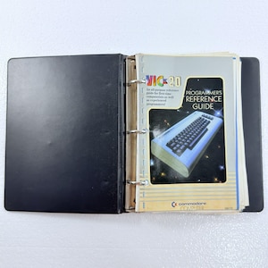 May include: A black three-ring binder containing a VIC-20 Programmer's Reference Guide. The cover features a graphic of a VIC-20 computer, the text "VIC-20", "An all-purpose reference guide", and the Commodore Computer logo on a light background.
