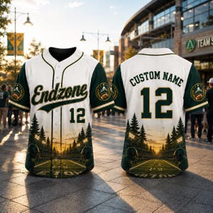 May include: A white and dark green button-up baseball jersey featuring the text Endzone and the number 12 on the front, with Custom Name and the number 12 on the back. The design includes a graphic of a football field at sunset with pine trees.