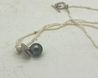 Delicate white seed pearl necklace with black Tahitian pearl pendant, hammered with sterling silver