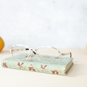 Puede incluir: Una taza de cerámica blanca con un asa negra y el texto "But First, Coffee" en un estilo manuscrito. La taza está sobre una superficie blanca. La taza mide 10 cm de alto.