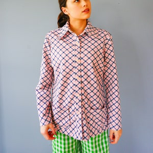 May include: A pink and blue plaid long-sleeved shirt with a collared neckline and button closure. The shirt has two patch pockets on the front.