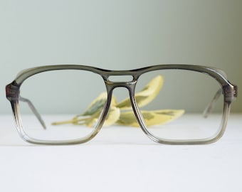 May include: A pair of grey plastic spectacles with clear lenses. The spectacles have a simple, classic design.