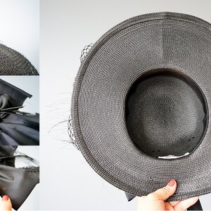 May include: A black straw hat with a wide brim and a black satin bow. The bow has a jeweled pin with green, pink, and clear stones.
