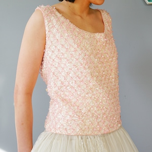 Pu&ograve; includere: Un top rosa senza maniche con paillettes e scollo rotondo. Il top &egrave; realizzato in un tessuto morbido e delicato ed &egrave; perfetto per un'occasione speciale.