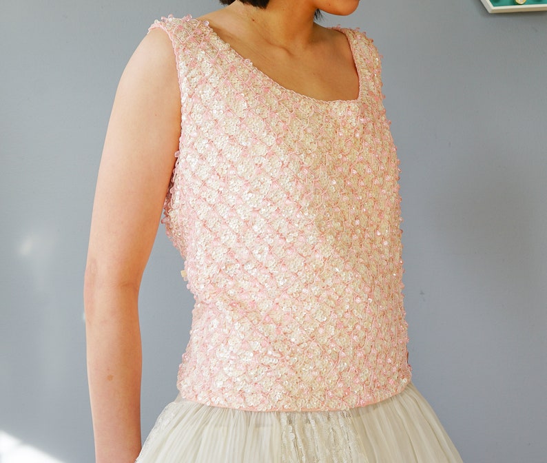Pu&ograve; includere: Un top rosa senza maniche con paillettes e scollo rotondo. Il top &egrave; realizzato in un tessuto morbido e delicato ed &egrave; perfetto per un'occasione speciale.