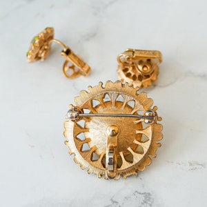 Peut inclure: Une broche dor&eacute;e avec un motif de filigrane et des strass verts. La broche a un fermoir &agrave; aiguille et un fermoir de s&eacute;curit&eacute;.