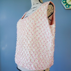 Pu&ograve; includere: Un top senza maniche di paillettes rosa e bianco. Il top &egrave; realizzato con piccole paillettes rotonde che sono cucite insieme in un motivo. Le paillettes sono di colore rosa chiaro con una lucentezza bianca.