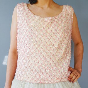 Pu&ograve; includere: Un top senza maniche di paillettes rosa e bianco con scollo rotondo.