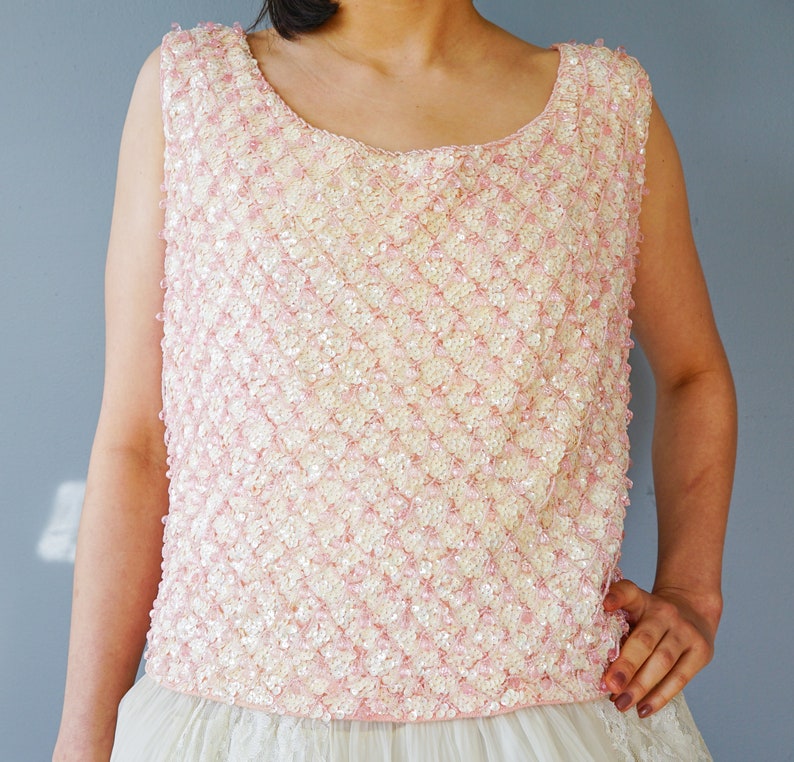 Pu&ograve; includere: Un top senza maniche di paillettes rosa e bianco con scollo rotondo.