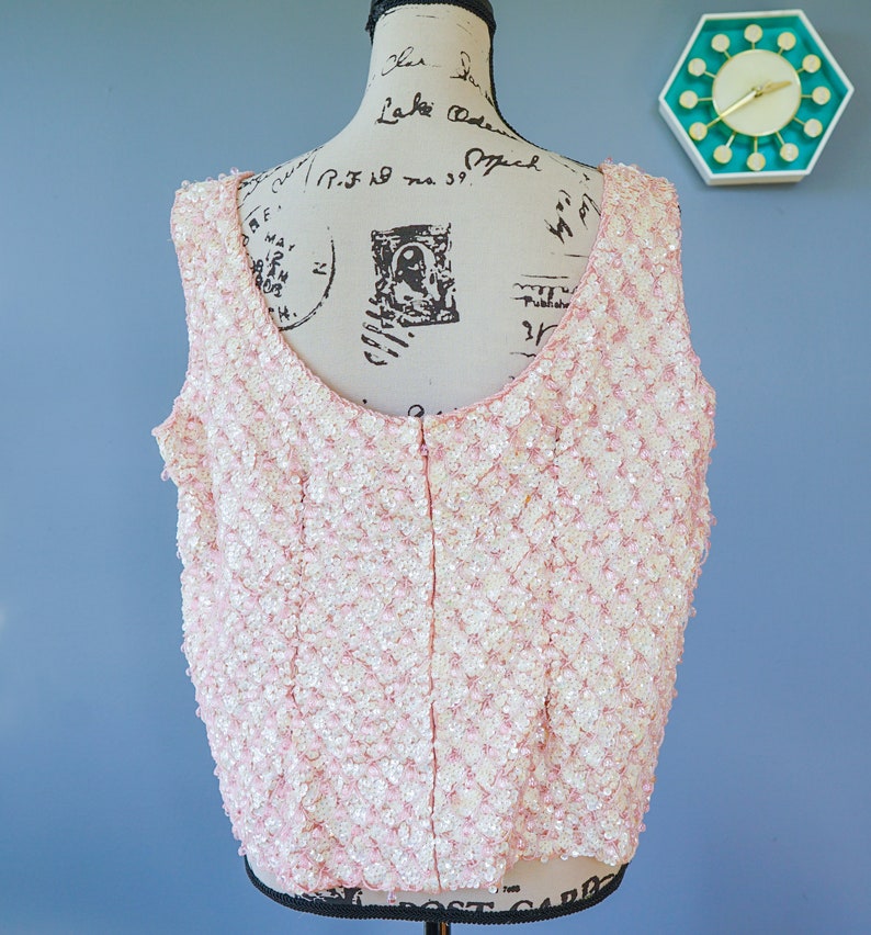 Pu&ograve; includere: Un top rosa senza maniche con una cerniera sul retro. Il top &egrave; ricoperto di paillettes.