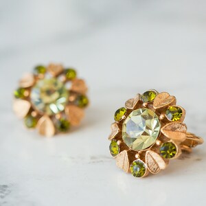 Peut inclure: Une paire de boucles d'oreilles en or avec des strass verts et vert clair dispos&eacute;s en forme de fleur.