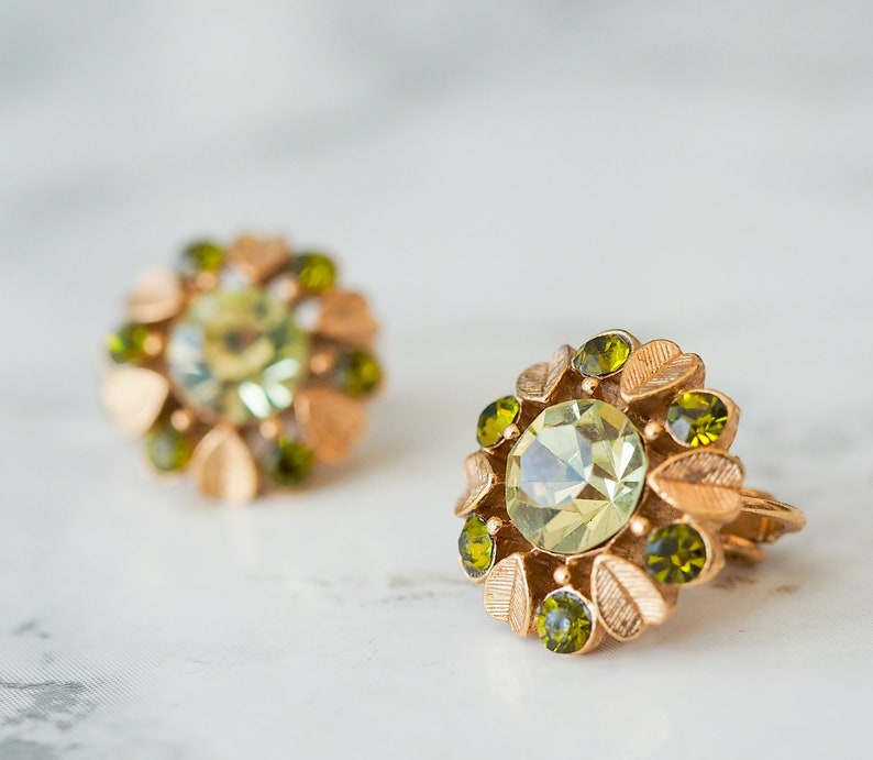 Peut inclure: Une paire de boucles d'oreilles en or avec des strass verts et vert clair dispos&eacute;s en forme de fleur.