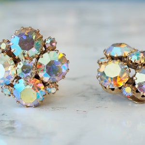 May include: A pair of iridescent gold tone clip-on earrings with a cluster of faceted rhinestones.