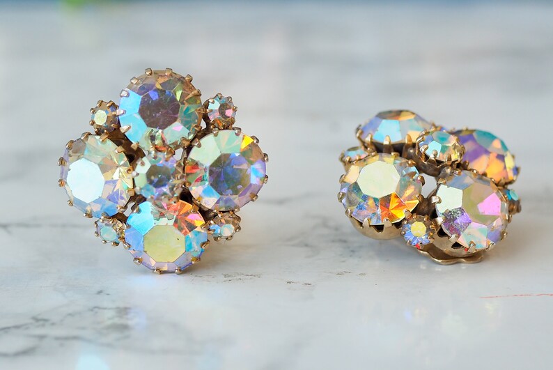May include: A pair of iridescent gold tone clip-on earrings with a cluster of faceted rhinestones.