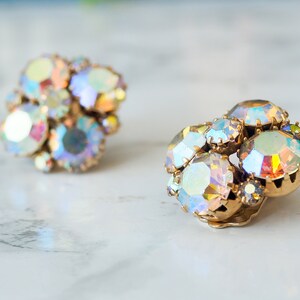 May include: A pair of iridescent gold tone clip-on earrings with a cluster of faceted rhinestones.